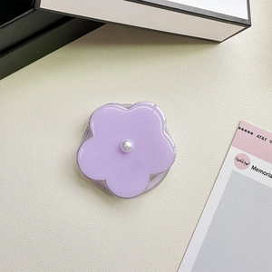Macro detail of a lavender flower phone grip with a white pearl on a beige leather texture