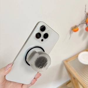 Close-up of translucent matte fish-shaped magnetic phone holder in warm home setting