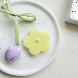 Detail of yellow flower phone grip with pearl center on aesthetic ceramic tray
