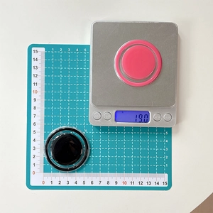 Détail d'un support MagSafe rose et noir posé sur une balance numérique de précision