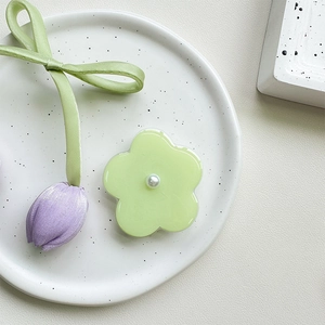 Macro detail of floral phone grip with white pearl center and purple satin tulip ribbon