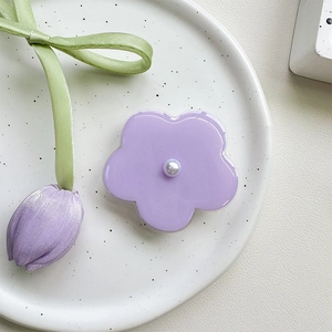 Macro detail of lavender flower phone grip with a glossy faux pearl center on white plate