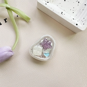 Close-up of heart and star resin phone grip with silver foil on leather background