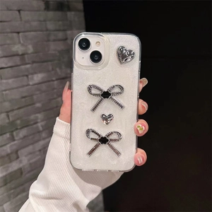 Detail of luxury iPhone case with silver glitter, rhinestones bow, and heart charms