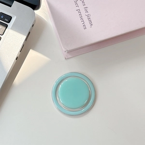 Détail du support MagSafe vert menthe sur bureau blanc avec ordinateur et livre