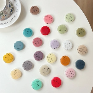Close-up of colorful resin round dot grips for phone sockets on a white surface