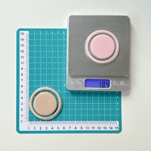 Macro detail of round MagSafe phone grips in pink and beige on a scale weighing 18.4g