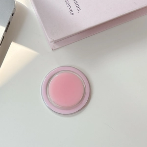 Vue macro d'un support de téléphone magnétique rond rose sur un bureau blanc épuré