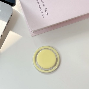 Détail d'un support de téléphone magnétique rond jaune clair à côté d'un ordinateur portable