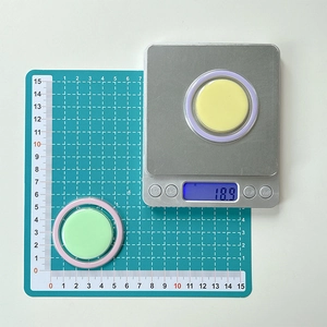 Close-up of two round colorful phone grips on a digital scale showing 18.9g weight