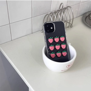 Detail of 3D pink strawberry patterns on black iPhone case in a white ceramic mug