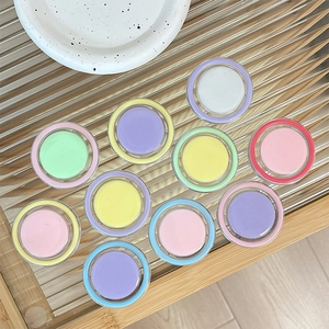 Colorful set of 10 macaron cream eyeliner jars on a glass tray in minimalist style