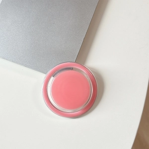 Detail view of a round pink cosmetic balm in a clear container on a desktop