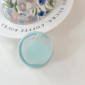 Dettaglio del supporto per telefono a forma di mela blu opaco su un piatto di ceramica