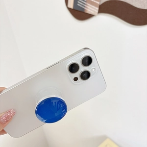 Macro shot of a dark blue glass phone grip attached to the back of a white smartphone