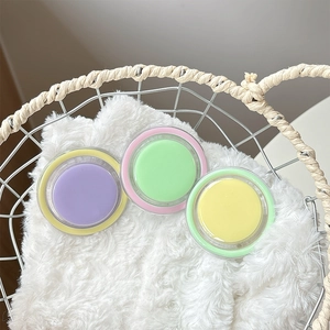 Three colorful round solid balms in purple, green, and yellow inside a white basket