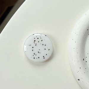 Detail of round white phone socket with black ink splatter pattern and glossy resin finish