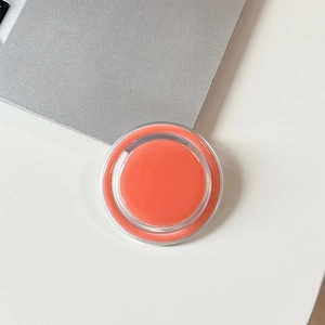 Close-up of a circular orange magnetic phone grip on a modern desk setup