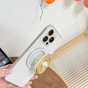 Detail view of MagSafe phone grip with gold oval metal base and elegant white pearl inlay