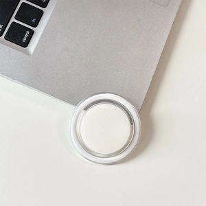 Macro view of minimalist magnetic round grip stand on a silver laptop surface