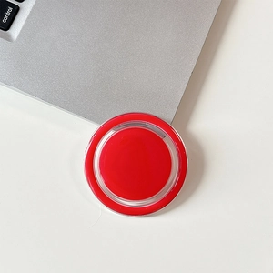Macro shot of red magnetic phone grip on white desk with laptop keyboard detail