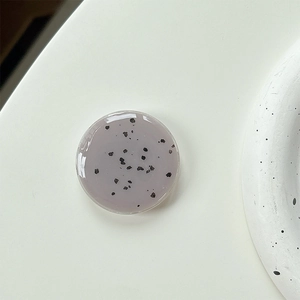 Macro detail of round minimalist phone grip with speckled stone texture on clean background