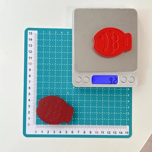 Detail of red fish-shaped leather phone grip with scale embossing and weight measurement