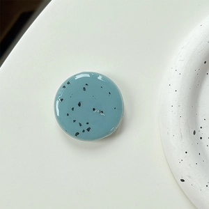 Macro shot of minimalist blue phone grip with black ink splatter and glossy finish