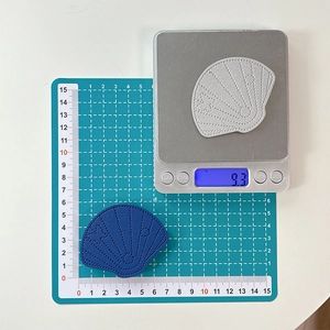 Macro view of shell-shaped embroidered patches showing weight and size measurement