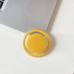 Macro top view of yellow magnetic circular phone grip on silver laptop surface