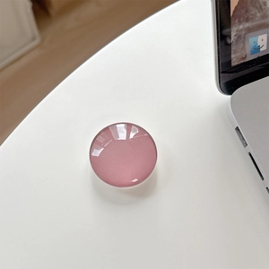 Detail of round dried rose pink crystal glass phone grip on a white desk setup