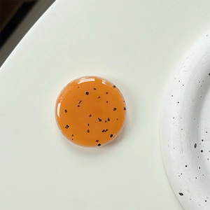 Detail view of round translucent orange resin phone grip with black seed speckles