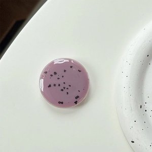 Macro shot of minimalist lavender resin phone grip with artistic black speckle patterns