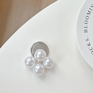 Detailed close-up of four white pearls on a silver ring phone stand with soft lighting