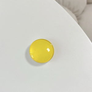 Close-up of a glossy yellow crystal glass round phone stand with smooth reflective surface