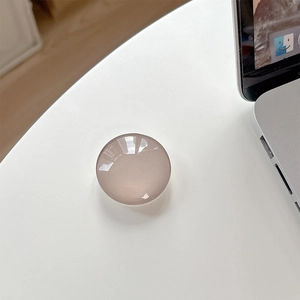 Macro detail of round crystal glass phone grip showing glossy translucent finish