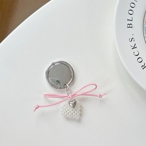 Detail of pink bow and heart pearl pendant on a polished silver phone ring holder