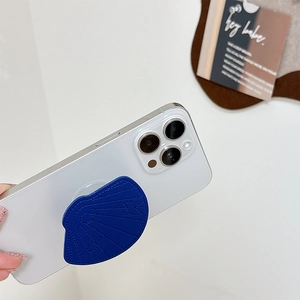 Detail of blue shell-shaped leather phone grip with butterfly stitching on white iPhone