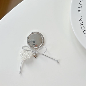 Detail of heart-shaped pearl pendant and silver bow on mirror phone socket