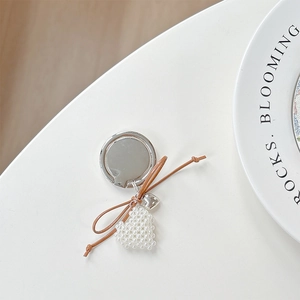 Detail of silver bow and pearl heart phone ring holder with stylish brown leather accent