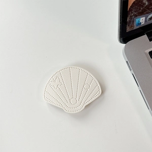 Close-up of white shell-shaped leather phone stand with fine stitching and butterfly pattern