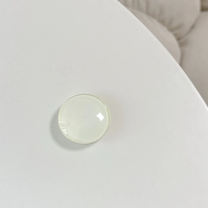 Macro detail of clear round crystal glass phone grip showing smooth polished surface