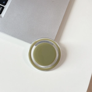 Close-up of olive green magnetic phone socket on a white desk with laptop keyboard