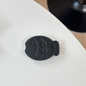 Macro shot of black leather fish phone grip with embossed smiley face and texture