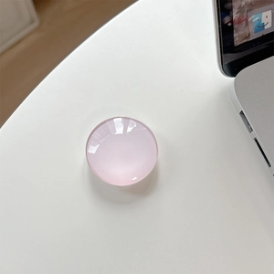 Top view of a pink translucent crystal glass phone grip showing high-gloss texture on white desk