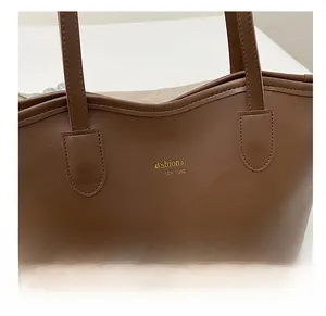 Λεπτομέρεια από δερμάτινη υφή και χρυσά γράμματα σε μεγάλη γυναικεία τσάντα tote
