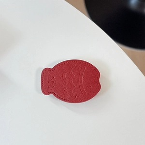 Detail of red fish-shaped leather phone grip with lychee grain and fine stitching