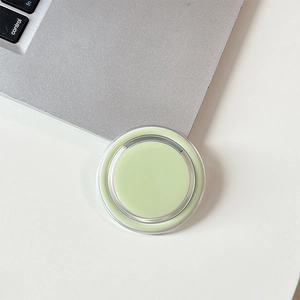 Close-up of minimalist mint green magnetic phone socket grip on a white desk setup