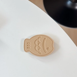 Close-up of khaki leather fish phone socket with detailed stitching and embossed fish design