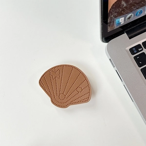 Macro detail of brown faux leather shell-shaped phone stand with stitched butterfly accent